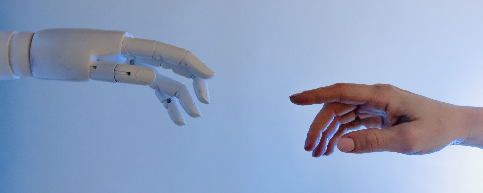 A human hand reaching towards a robotic hand symbolizing technology and connection.